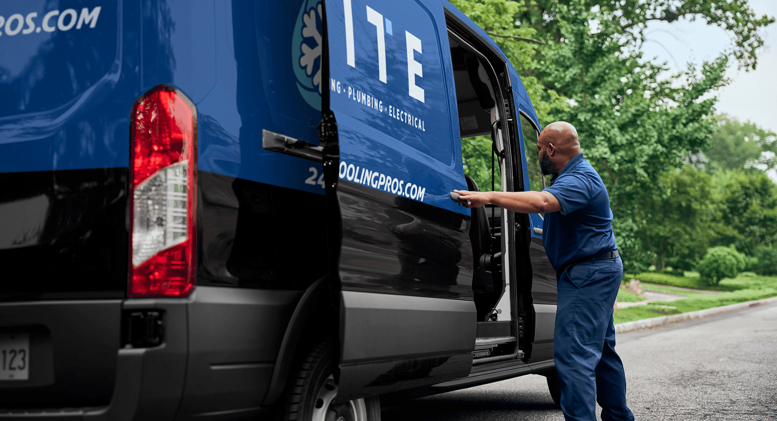 A professional Elite technician opening a service van on a residential street, ready to provide home HVAC, plumbing, and electrical services.
